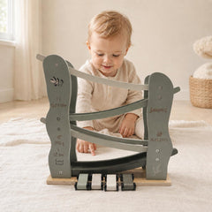 Baby spielt mit einer personalisierten Label Label Holz-Rennbahn in Salbeigrün mit vier Autos, Name und Geburtsdaten – besonderes Babygeschenk zur Geburt.