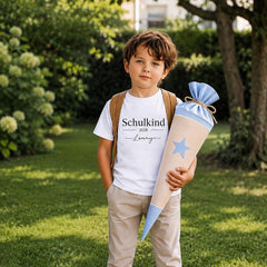 Junge trägt personalisiertes Schulkind T-Shirt 2028 mit Namen Lenny und blauer Schultüte im Garten