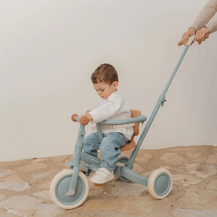 Kind sitzt auf dem Little Dutch Tricycle 4-in-1 in Blau mit Schubstange. Das Schiebedreirad bietet Sicherheit, Komfort und wächst vom Dreirad zum Laufrad für Kinder ab 1 Jahr mit.