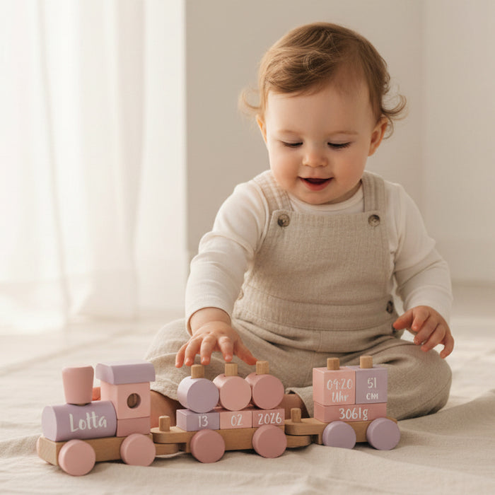 Baby spielt mit personalisiertem rosa small-foot-Holzzug aus Holz