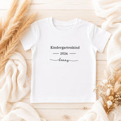 Personalisiertes Kindergartenkind T-Shirt 2026 mit Namen Lenny auf hellem Holzuntergrund mit Trockenblumen
