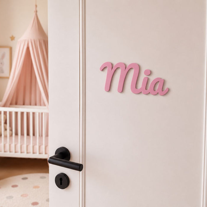 Personalisiertes Türschild Mia in Rosa an weißer Kinderzimmertür mit rosa Babyzimmer im Hintergrund