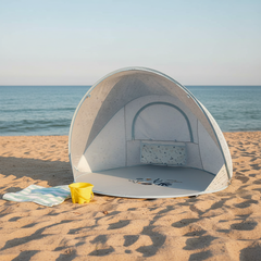 Blaue Strandmuschel für Babys und Kinder am Strand mit Meer im Hintergrund – UV Schutz Pop Up Strandzelt für sicheren Schatten ohne direkte Sonne
