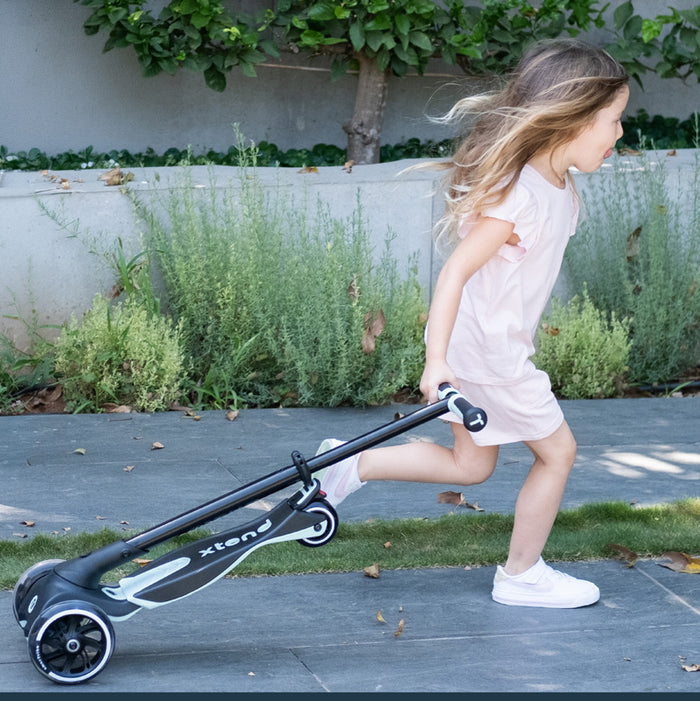 Kind zieht zusammenklappbaren Kinder Scooter hinter sich beim Gehen im Alltag