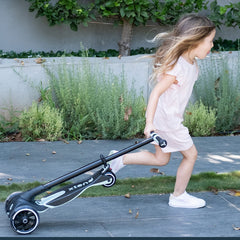 Kind zieht zusammenklappbaren Kinder Scooter hinter sich beim Gehen im Alltag
